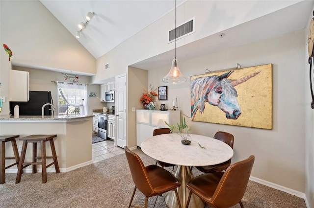 carpeted dining room with track lighting and high vaulted ceiling