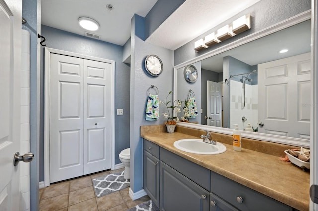 bathroom with vanity, toilet, a shower, and tile patterned floors