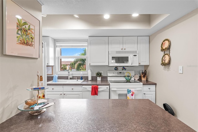 kitchen with white cabinets, white appliances, a textured ceiling, and sink