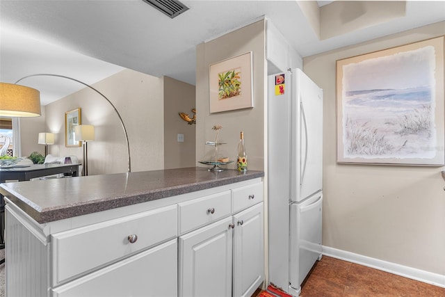 kitchen with kitchen peninsula, dark tile patterned floors, and white fridge