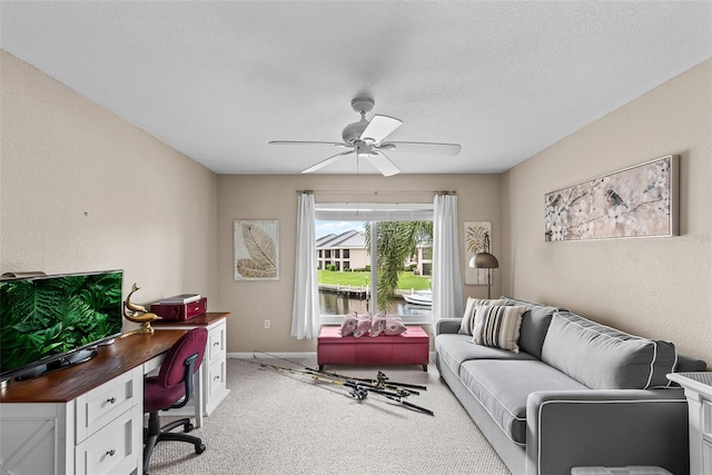 carpeted home office featuring a textured ceiling and ceiling fan