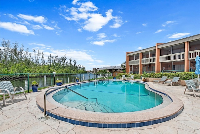 view of pool with a water view and a patio