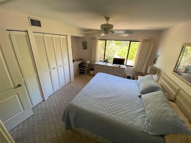 carpeted bedroom with ceiling fan and multiple closets