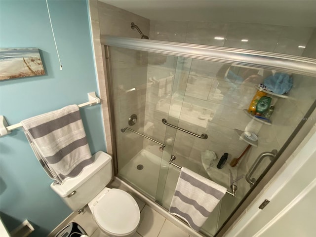 bathroom featuring a shower with shower door and toilet