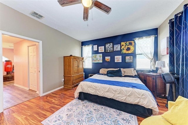 bedroom with ceiling fan, multiple windows, and hardwood / wood-style flooring