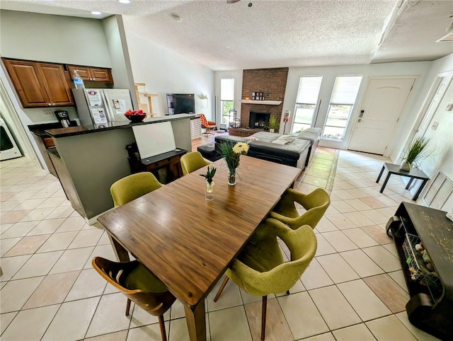 tiled dining area featuring a brick fireplace, a textured ceiling, and lofted ceiling