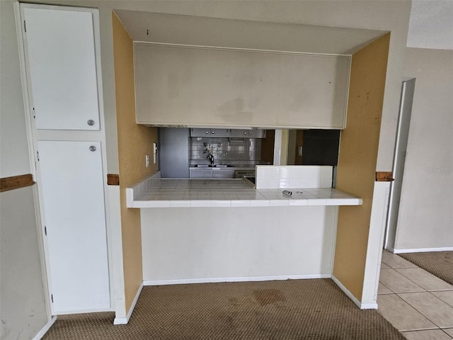 kitchen with white cabinetry, tile counters, and light colored carpet