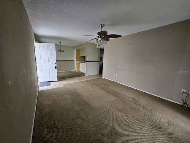 spare room featuring a textured ceiling, ceiling fan with notable chandelier, and light carpet