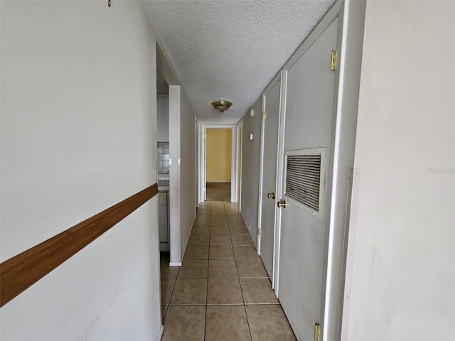 corridor with light tile patterned floors and a textured ceiling