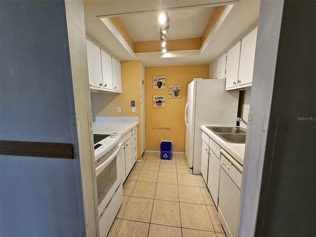 kitchen with white appliances, a tray ceiling, white cabinetry, and sink