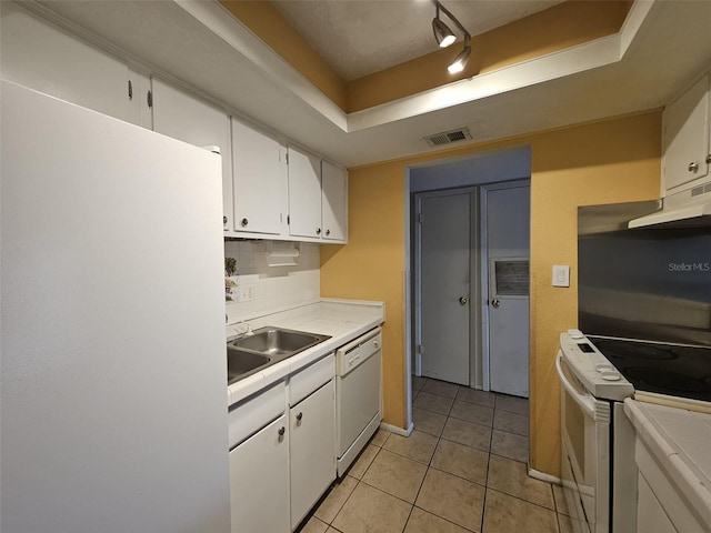 kitchen with sink, a raised ceiling, light tile patterned flooring, white appliances, and white cabinets