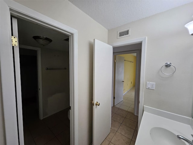 bathroom featuring a textured ceiling, tile patterned floors, and sink