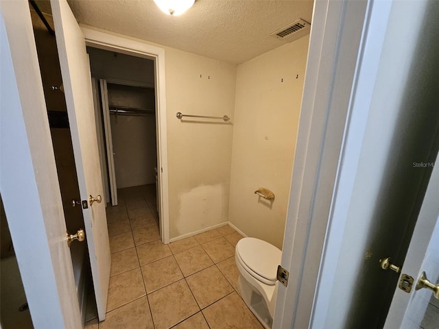 bathroom featuring tile patterned floors, a textured ceiling, and toilet