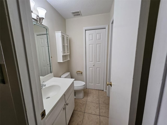 bathroom featuring tile patterned floors, vanity, a textured ceiling, and toilet