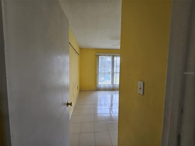 hall featuring light tile patterned floors and a textured ceiling