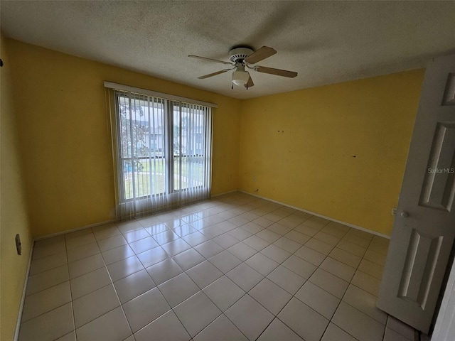 spare room with ceiling fan, light tile patterned floors, and a textured ceiling