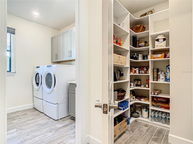 laundry area featuring washer and dryer, cabinets, and light hardwood / wood-style floors