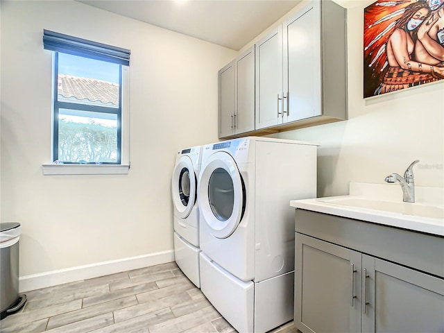 laundry room with sink, light hardwood / wood-style floors, cabinets, and separate washer and dryer