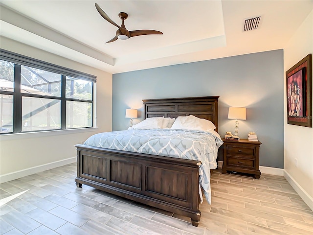 bedroom with a tray ceiling, ceiling fan, and light hardwood / wood-style floors