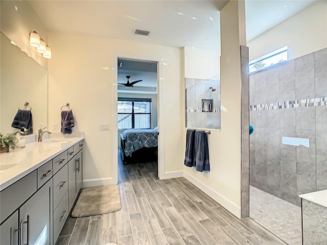 bathroom with tiled shower, ceiling fan, hardwood / wood-style flooring, and vanity