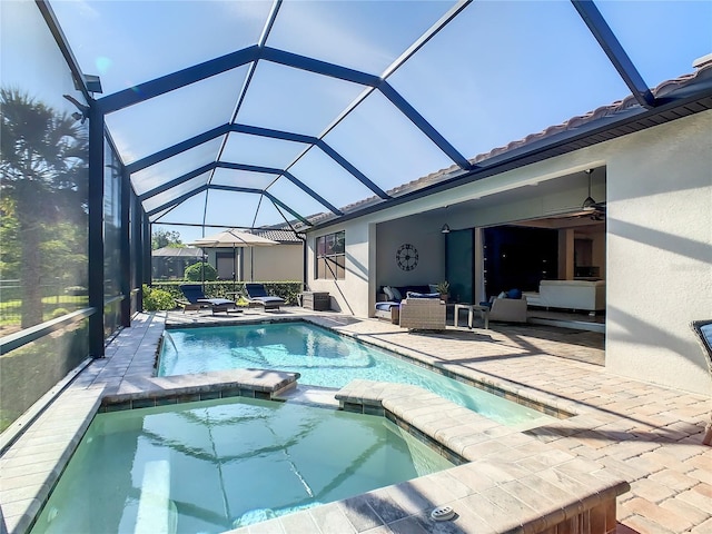 view of pool with outdoor lounge area, glass enclosure, a patio area, and an in ground hot tub