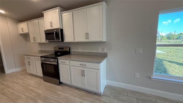 kitchen with light stone counters, white cabinets, and stainless steel appliances