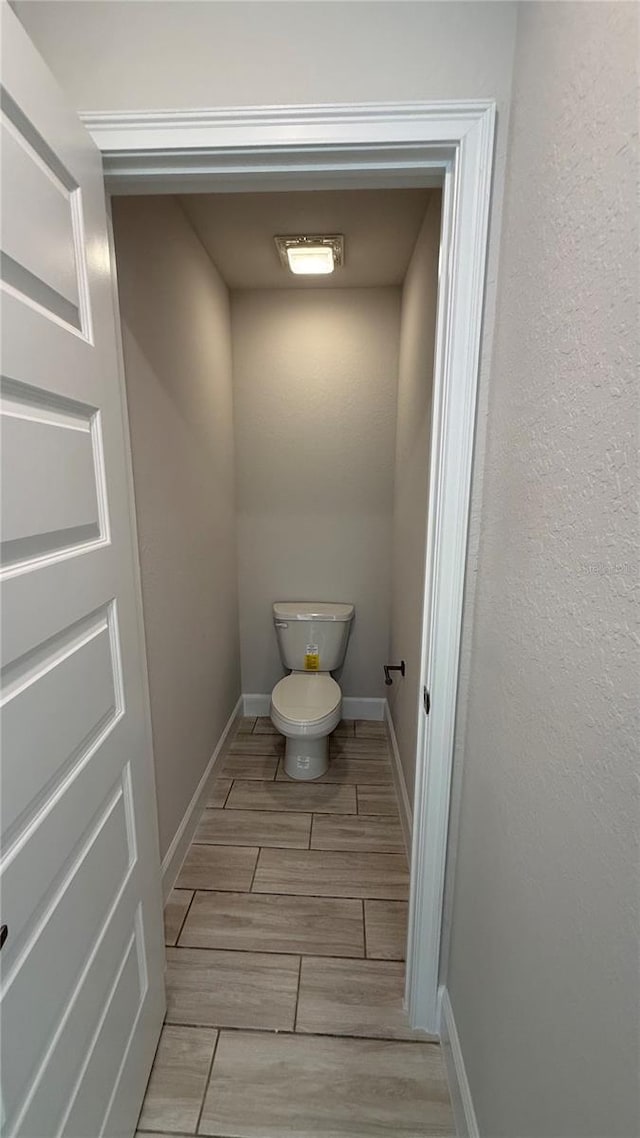 bathroom featuring wood tiled floor, toilet, and baseboards