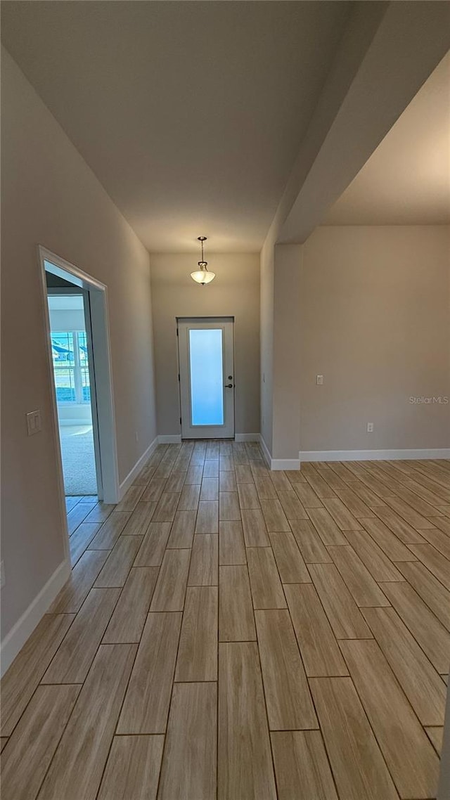 unfurnished room with wood finish floors, a wealth of natural light, and baseboards