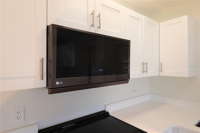 room details featuring white cabinetry and black range oven