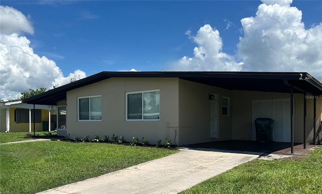 view of front of house featuring driveway, an attached carport, a front lawn, and stucco siding