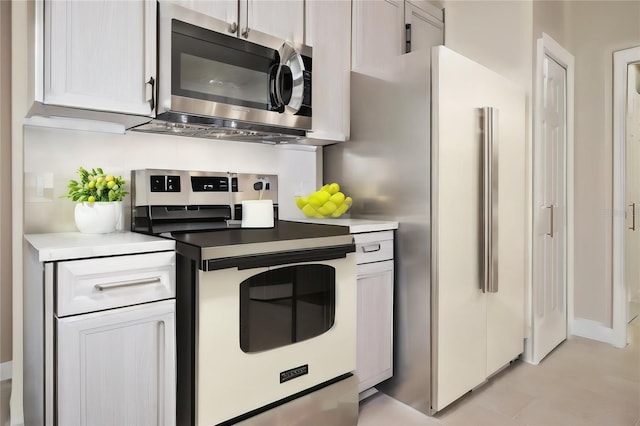 kitchen with stainless steel electric range oven, light countertops, and freestanding refrigerator