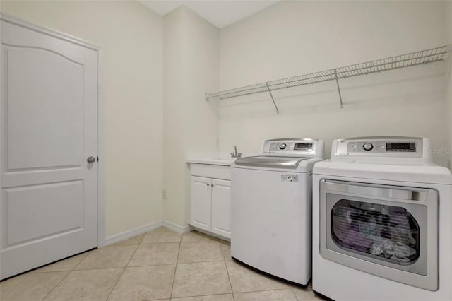 clothes washing area with cabinets, separate washer and dryer, sink, and light tile patterned floors