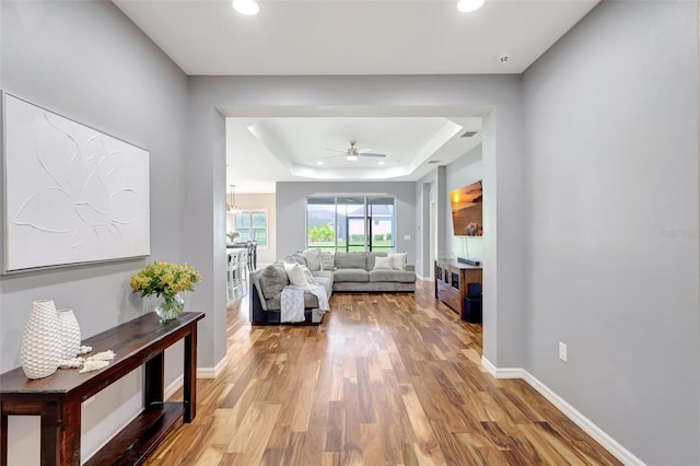 corridor with light hardwood / wood-style flooring and a raised ceiling