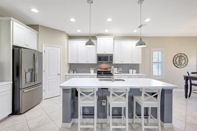 kitchen with white cabinets, stainless steel appliances, and a center island with sink