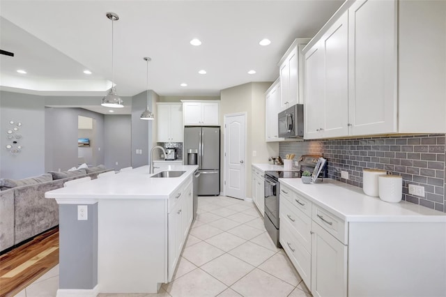 kitchen with pendant lighting, a kitchen island with sink, white cabinets, light tile patterned flooring, and stainless steel appliances