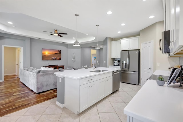 kitchen with ceiling fan, sink, stainless steel appliances, a center island with sink, and white cabinets