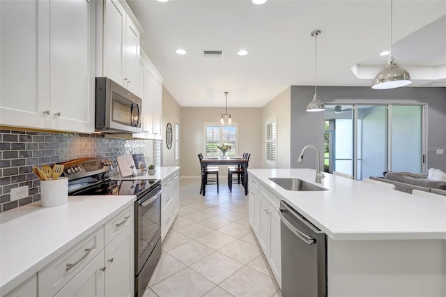 kitchen with white cabinets, appliances with stainless steel finishes, a kitchen island with sink, and sink