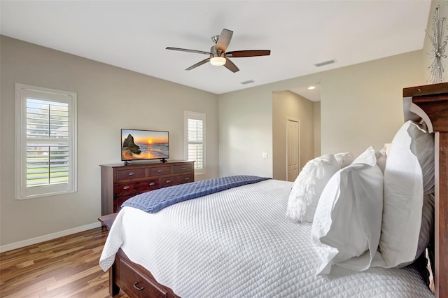 bedroom featuring multiple windows, a closet, light hardwood / wood-style floors, and ceiling fan