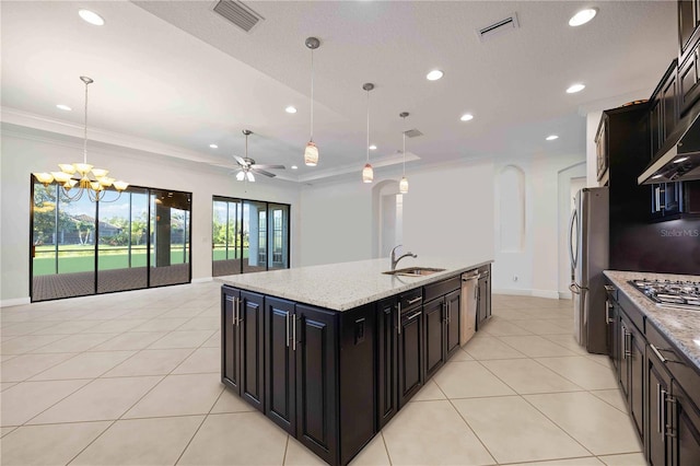 kitchen featuring a kitchen island with sink, ceiling fan with notable chandelier, sink, decorative light fixtures, and light stone counters