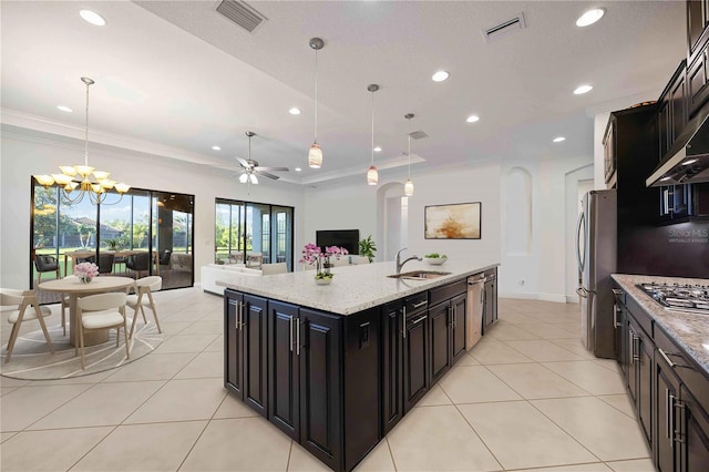 kitchen featuring pendant lighting, ceiling fan with notable chandelier, a center island with sink, and sink