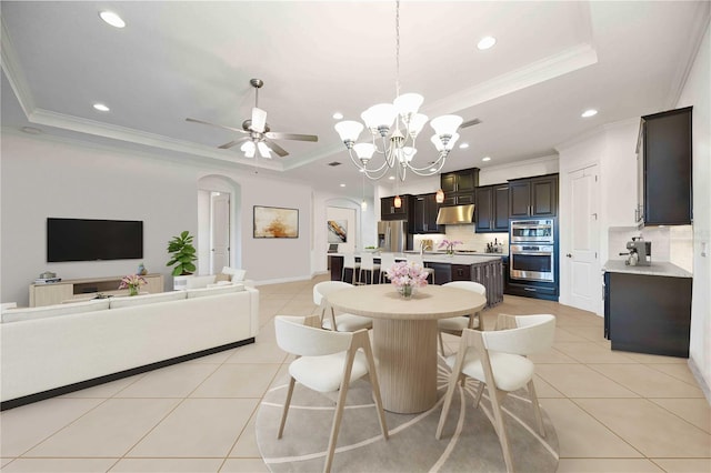 tiled dining room featuring ceiling fan with notable chandelier, a raised ceiling, and crown molding