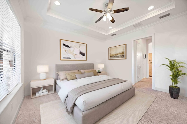 carpeted bedroom with a tray ceiling, ceiling fan, and crown molding