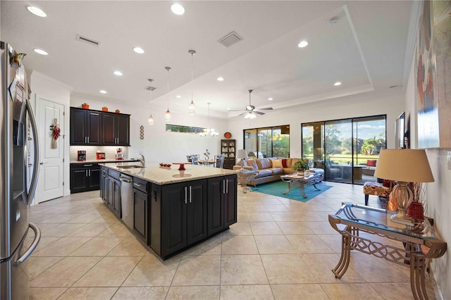 kitchen featuring ceiling fan, pendant lighting, a center island with sink, light tile patterned floors, and appliances with stainless steel finishes