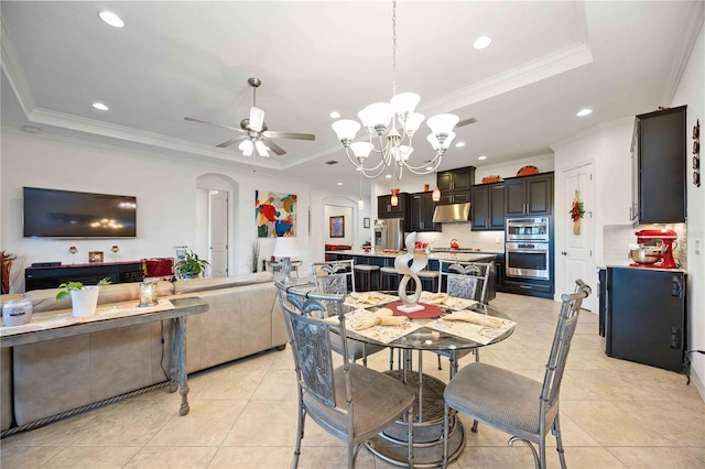 dining area featuring ceiling fan with notable chandelier, light tile patterned flooring, a raised ceiling, and ornamental molding