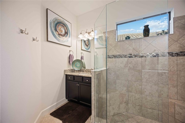 bathroom featuring tile patterned flooring, vanity, and a tile shower