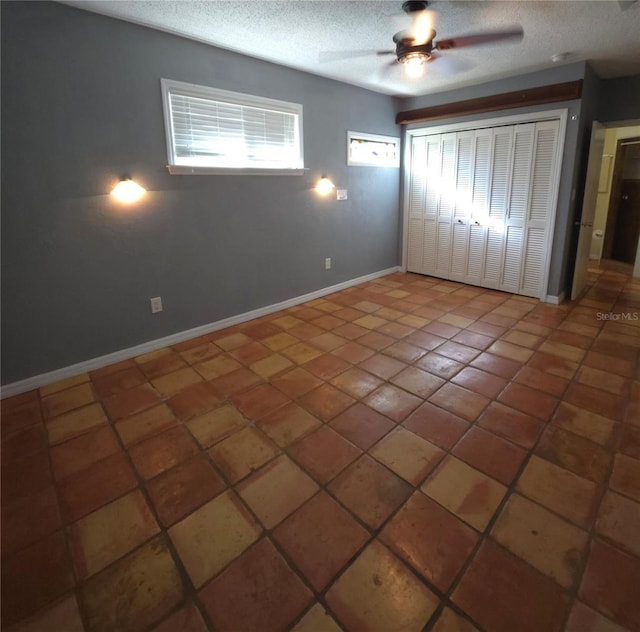 unfurnished bedroom with tile patterned flooring, ceiling fan, a textured ceiling, and a closet