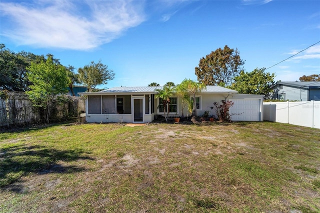 back of property featuring a sunroom, a garage, and a yard