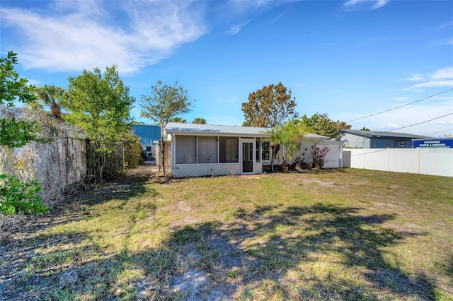 rear view of property with a lawn and a sunroom