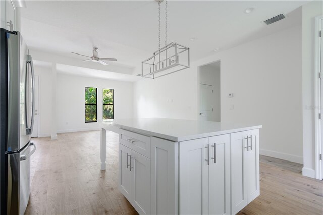 kitchen featuring light hardwood / wood-style flooring, a center island, stainless steel refrigerator, white cabinetry, and ceiling fan