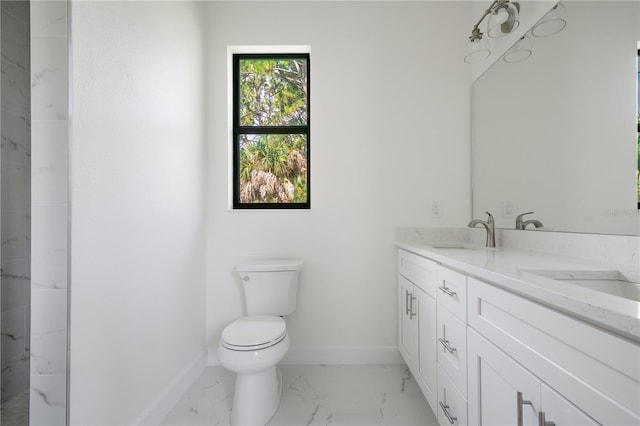 bathroom featuring marble finish floor, double vanity, toilet, a sink, and baseboards